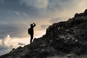 A man looking up a mountain at dusk. - Rimo3 Podcast